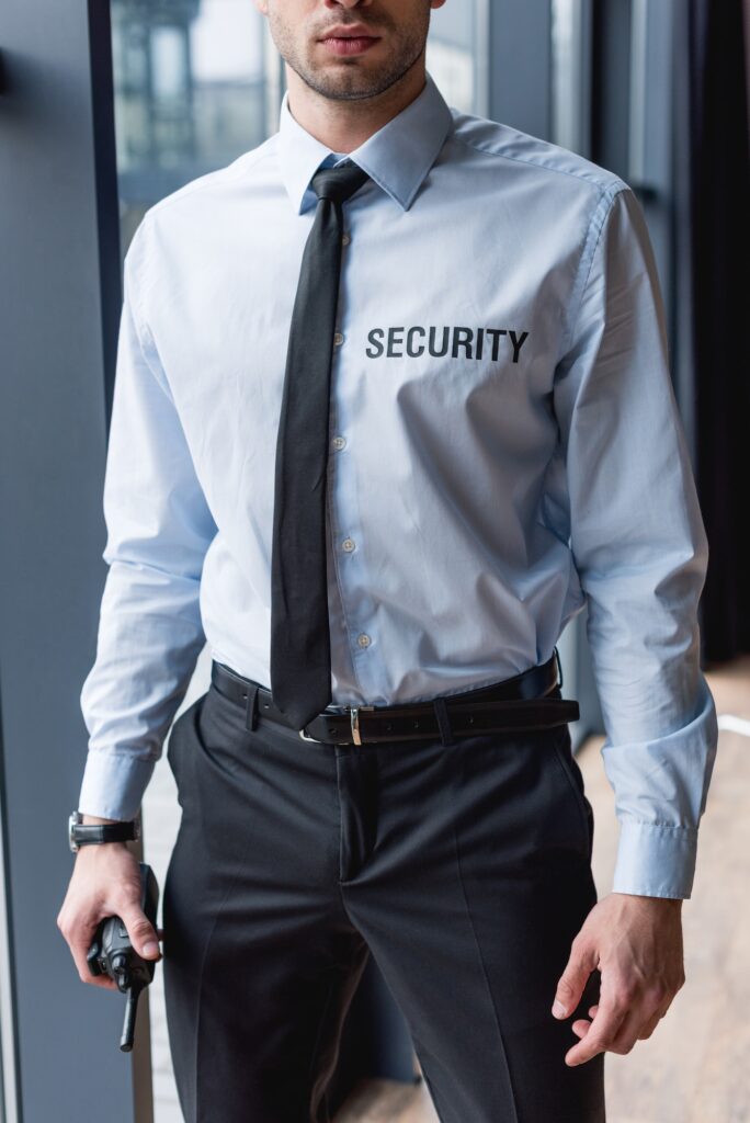 partial view of handsome guard in suit holding walkie-talkie