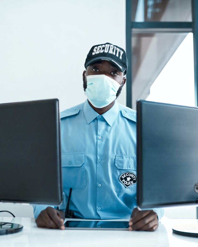 Portrait of a confident masked young security guard on duty at the front desk of an office